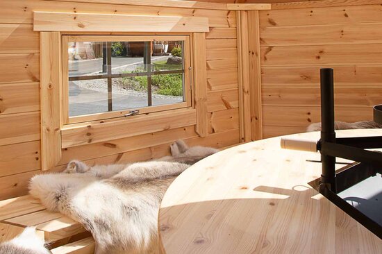 Heller Innenraum einer Grillkota von Finnhaus Wolff mit Tierfell auf der Sitzbank aus Holz.